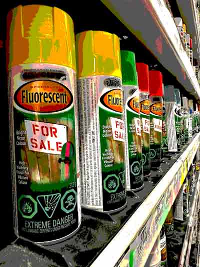 Toxic products on the shelf. Cans of aerosol paint with flammable and toxic poison symbols. 
