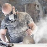 Worker cutting quartz countertop or engineered stone with dust flying.