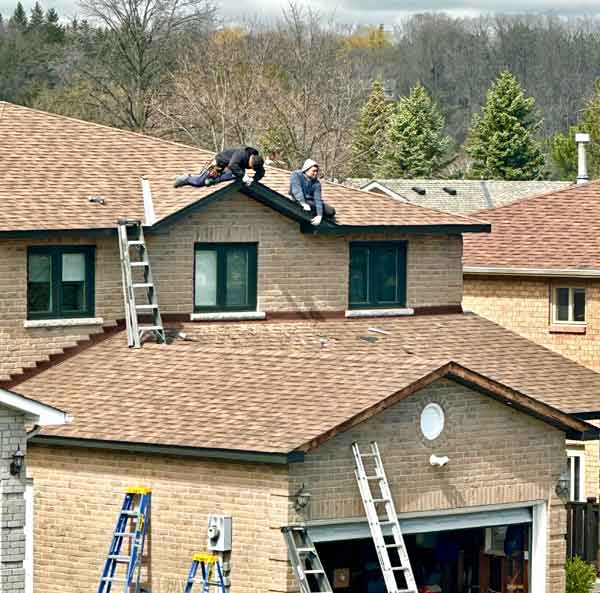 Roofers precariously close to the edge of a residential roof. The most Dangerous jobs. Free WHMIS training, Free transportation of dangerous goods training.